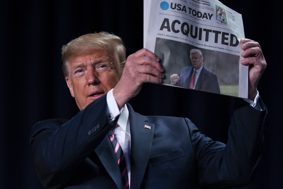 Trump holding a newspaper announcing his acquittal.